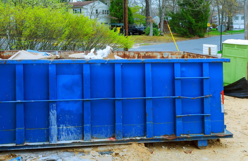 Blur dumpster, recycle waste and garbage bins near new construction of appartment houses building